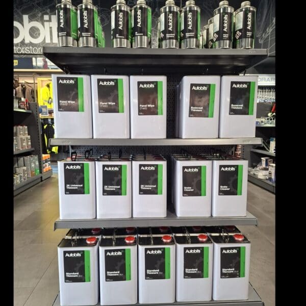 Display shelves in an automotive store showcasing Autobits branded products including thinners, brake cleaner, and panel wipes in metal containers.