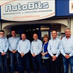 Team of staff members standing outside the AutoBits car parts and accessories shop beneath the AutoBits storefront sign.