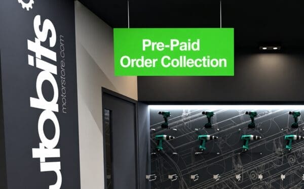 Interior of a modern tool store with a large “Pre-Paid Order Collection” sign hanging above a display of green power drills on a wall, branded “tools motorsstore.com”.